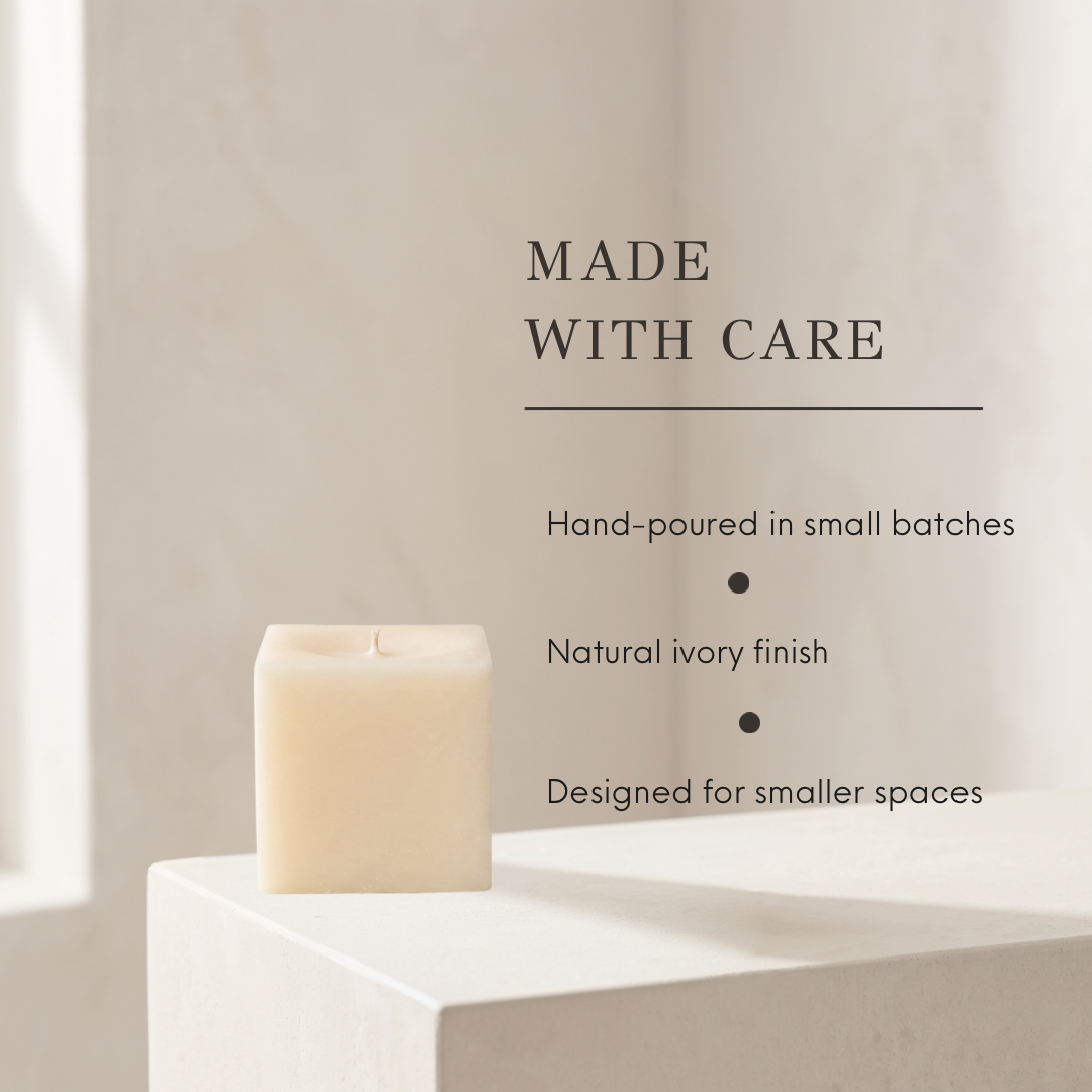 A natural ivory square candle sits on a white pedestal against a warm beige wall, with text on the right reading &