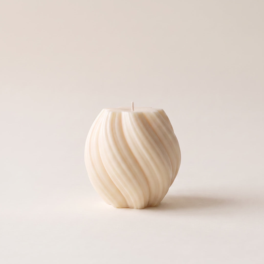 An off-white textured candle with a ribbed, spiral pattern, standing upright on a neutral cream background.