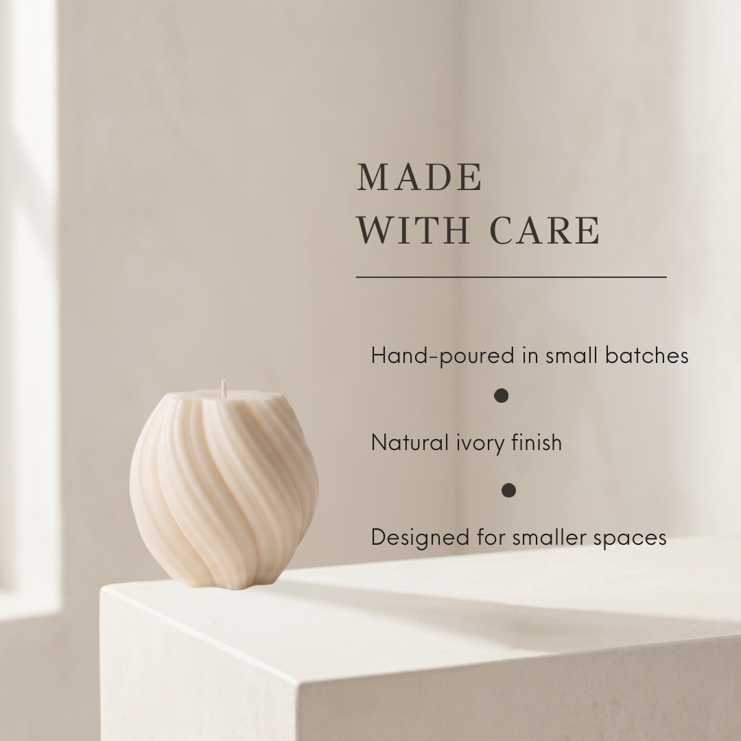 A sculptural ribbed candle in a warm ivory finish sits on a white pedestal against a softly lit beige wall, with text reading “MADE WITH CARE” and additional product details beside it.