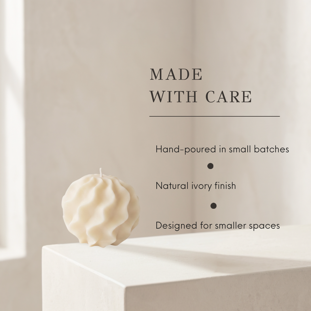 A sculptural, hand-poured candle in a natural ivory finish sits on a white pedestal against a warm beige background. Text on the right reads &