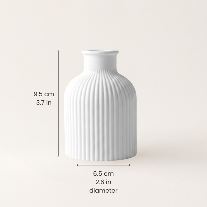 A white ribbed ceramic vase centered on a light beige background, with dimension lines and text showing a height of 9.5 cm (3.