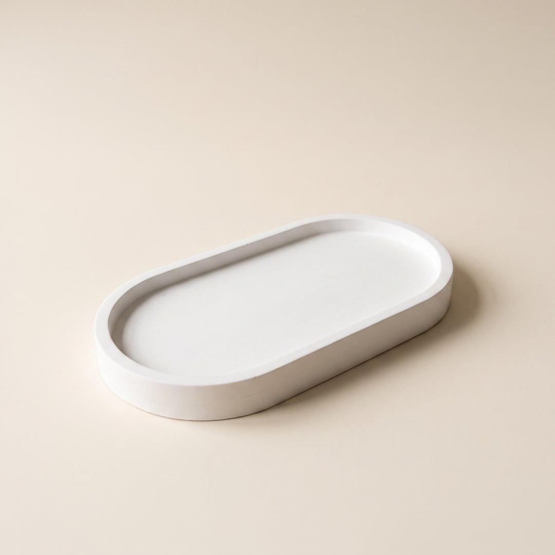 A minimalist white oval tray with a raised rim, photographed on a clean, solid beige background.